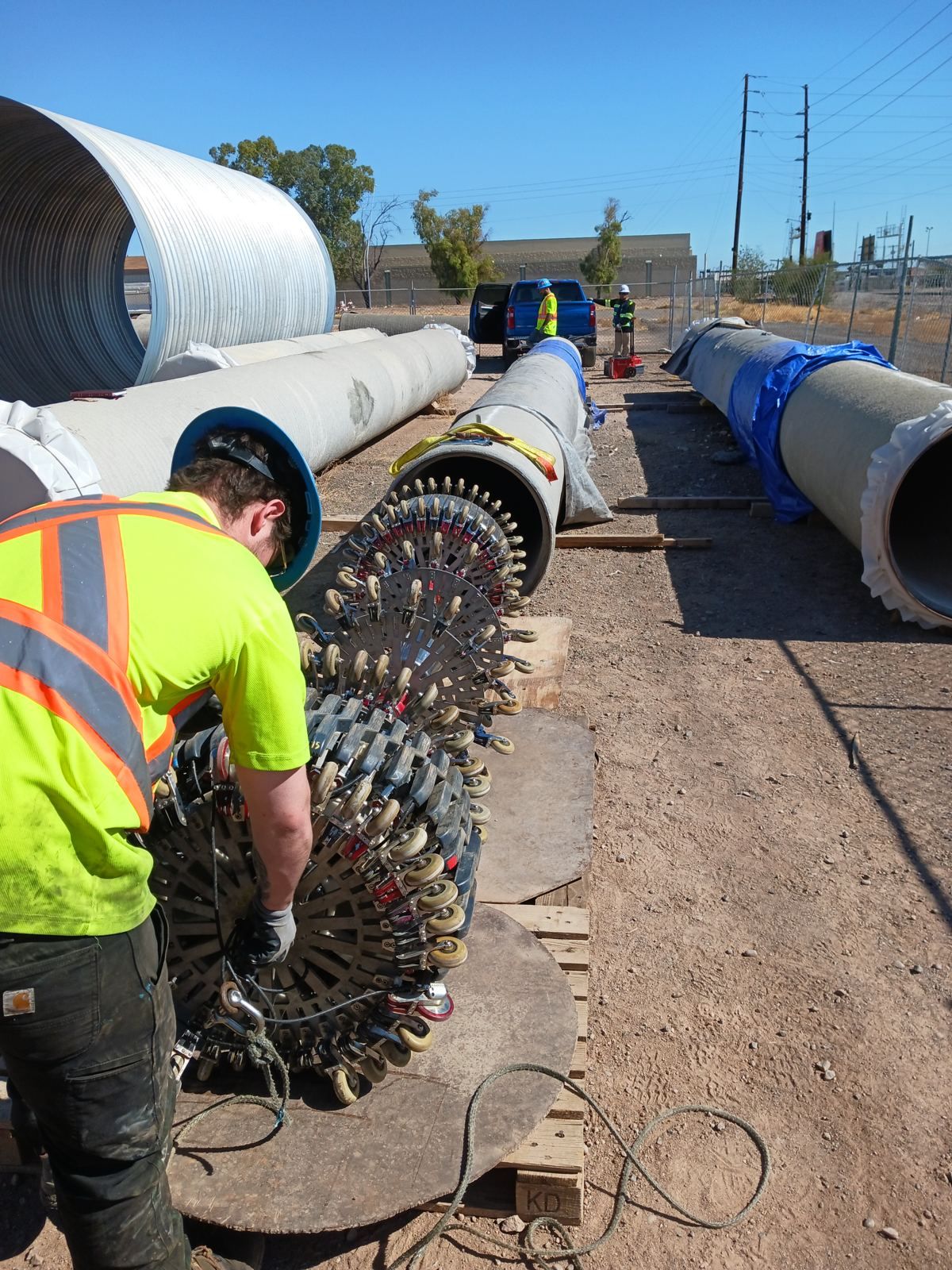 Field crew assembling a remote field testing inspection tool beside pipe sections